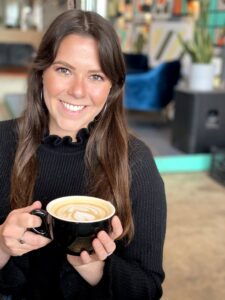 brunette drinking a latte with foam art smiling