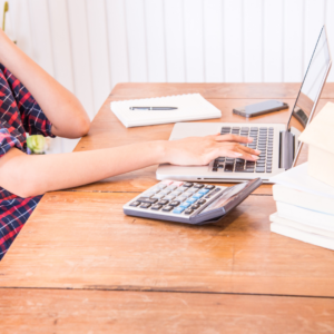 business owner typing on laptop next to a calculator